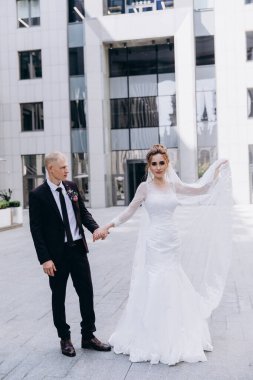 Güzel mutlu gelin ve damat şehirde yürüyor.         