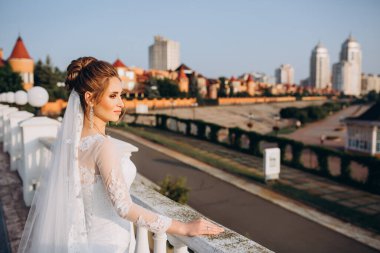 Şehirde poz veren zarif beyaz gelinlik içindeki güzel genç gelinin portresi.          