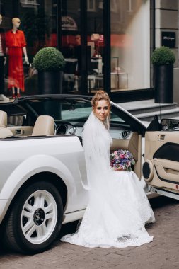 Gelinlik içinde elinde buket ve lüks bir arabada oturan genç gelin.   