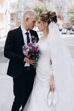 Güzel mutlu gelin ve damat şehirde yürüyor.         