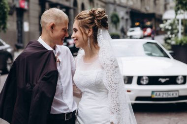 Güzel mutlu gelin ve damat şehirde yürüyor.         