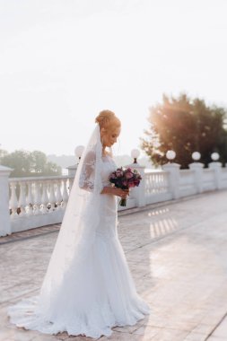 Gün batımında dışarıda poz veren gelinlik içindeki güzel gelinin portresi.        