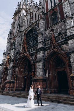 Güzel genç gelin ve damat eski kilisenin önünde yürüyor.        