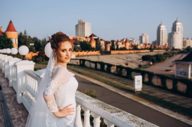 Şehirde poz veren zarif beyaz gelinlik içindeki güzel genç gelinin portresi.          