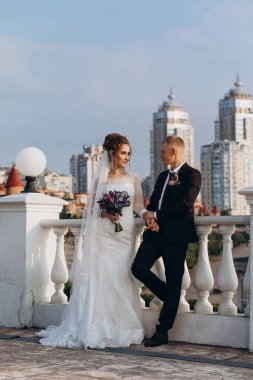 Güzel bir çift mutlu gelin ve damat şehirde birlikte poz veriyorlar.               