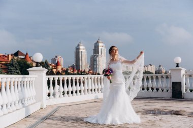 Şehirde poz veren zarif beyaz gelinlik içindeki güzel genç gelinin portresi.          