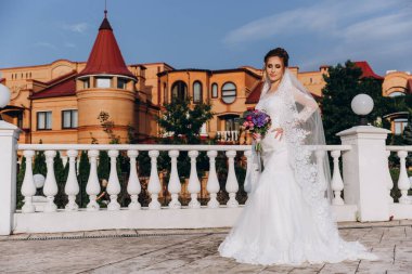 Şehirde poz veren zarif beyaz gelinlik içindeki güzel genç gelinin portresi.          