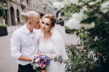 Güzel mutlu gelin ve damat şehirde yürüyor.         