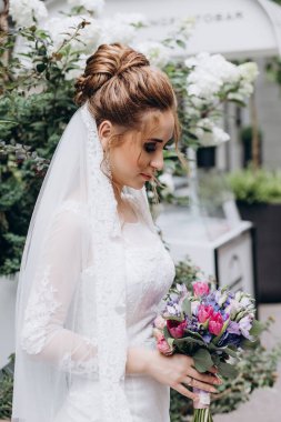 Şehirde poz veren zarif beyaz gelinlik içindeki güzel genç gelinin portresi.          