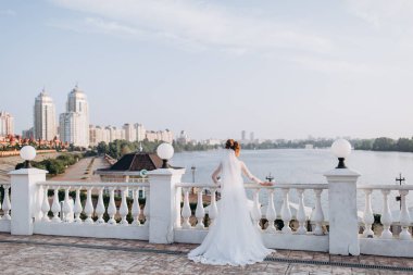 Köprüde durup nehire bakan genç gelinin arka manzarası