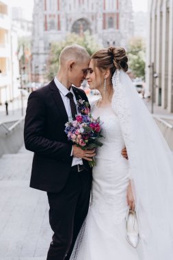 Güzel mutlu gelin ve damat şehirde yürüyor.         