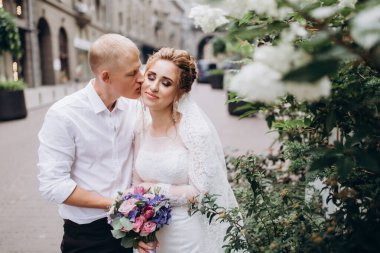 Güzel mutlu gelin ve damat şehirde yürüyor.         