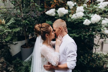 Mutlu çift gelin ve damat şehirde düğün günü sarılıp öpüşüyor..         