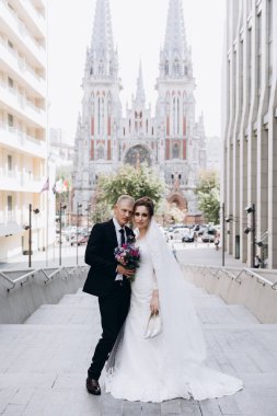 Güzel mutlu gelin ve damat şehirde yürüyor.         