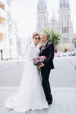 Güzel bir çift mutlu gelin ve damat şehirde birlikte poz veriyorlar.               