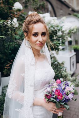 Şehirde poz veren zarif beyaz gelinlik içindeki güzel genç gelinin portresi.          