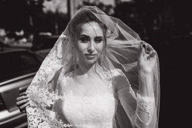 Şehirde poz veren zarif beyaz gelinlik içindeki güzel genç gelinin portresi.          