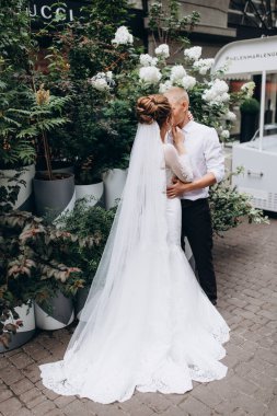 Mutlu çift gelin ve damat şehirde düğün günü sarılıp öpüşüyor..         