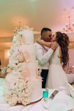 Güzel bir çift restoranda lezzetli bir pastanın yanında öpüşüyor. 