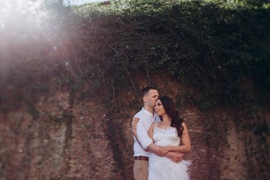 Gelin ve damat taş duvarın yanında poz veriyorlar.