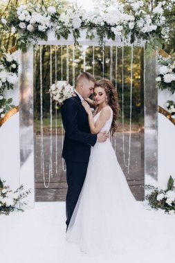 Genç bir düğün çifti, özel günlerinde güzel düğün süslemelerinin önünde romantik bir anın tadını çıkarır..