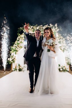 Genç bir düğün çifti, özel günlerinde güzel düğün süslemelerinin önünde romantik bir anın tadını çıkarır..