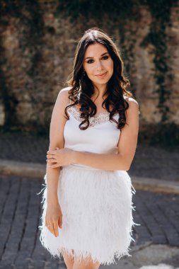 Parkta açık havada poz veren gelinlikli güzel bir kadının dikey fotoğrafı.