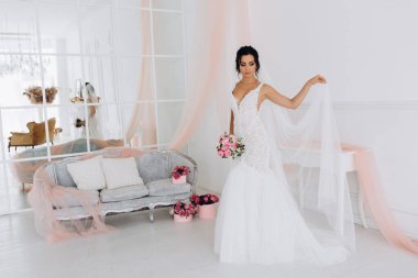 Beyaz gelinlik içinde güzel, genç bir gelin. Lüks içinde poz veriyor.        