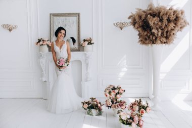 Beyaz gelinlik içinde güzel, genç bir gelin. Lüks içinde poz veriyor.        