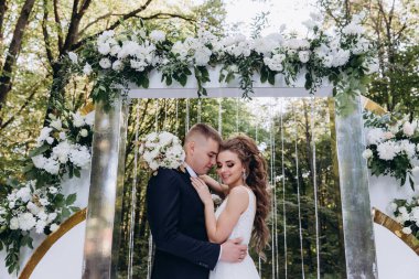 Genç bir düğün çifti, özel günlerinde güzel düğün süslemelerinin önünde romantik bir anın tadını çıkarır..