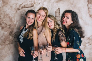 Stüdyoda şampanya kadehleriyle poz veren bir grup güzel genç kadın.