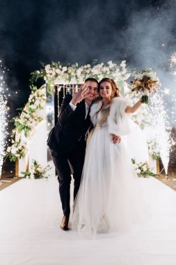 Genç bir düğün çifti, özel günlerinde güzel düğün süslemelerinin önünde romantik bir anın tadını çıkarır..