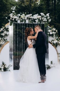 Genç bir düğün çifti, özel günlerinde güzel düğün süslemelerinin önünde romantik bir anın tadını çıkarır..