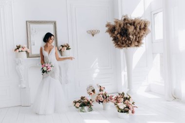 Beyaz gelinlik içinde güzel, genç bir gelin. Lüks içinde poz veriyor.        