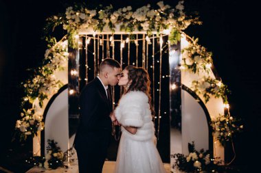 Genç bir düğün çifti, özel günlerinde güzel düğün süslemelerinin önünde romantik bir anın tadını çıkarır..