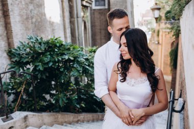 Güzel, genç bir çift eski kasabada birbirlerine sarılıp poz veriyorlar.