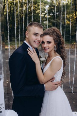 Genç bir düğün çifti, özel günlerinde güzel düğün süslemelerinin önünde romantik bir anın tadını çıkarır..