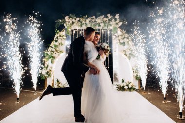 Genç bir düğün çifti, özel günlerinde güzel düğün süslemelerinin önünde romantik bir anın tadını çıkarır..