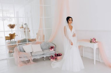 Beyaz gelinlik içinde güzel, genç bir gelin. Lüks içinde poz veriyor.        