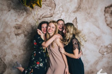 Stüdyoda balonlarla poz veren şenlikli elbiseli güzel genç kızlar.