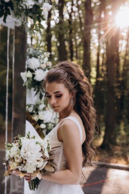 Genç ve güzel bir gelin, özel gününde göz kamaştırıcı düğün süslerinin önünde zarifçe poz verir..