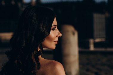 Genç esmer kadın akşam dışarıda poz veriyor. 