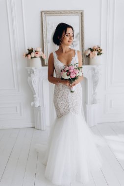 Beyaz gelinlik içinde güzel, genç bir gelin. Lüks içinde poz veriyor.        