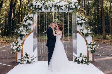 Genç bir düğün çifti, özel günlerinde güzel düğün süslemelerinin önünde romantik bir anın tadını çıkarır..