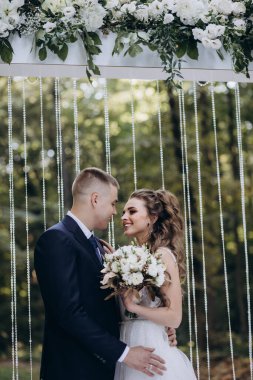 Genç bir düğün çifti, özel günlerinde güzel düğün süslemelerinin önünde romantik bir anın tadını çıkarır..