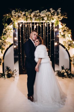 Genç bir düğün çifti, özel günlerinde güzel düğün süslemelerinin önünde romantik bir anın tadını çıkarır..