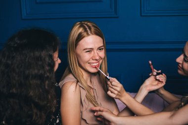 Güzel genç kız mutlu arkadaşlarla makyaj yapıyor.