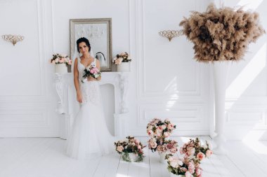 Beyaz gelinlik içinde güzel, genç bir gelin. Lüks içinde poz veriyor.        