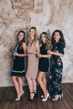 Stüdyoda şampanya kadehleriyle poz veren bir grup güzel genç kadın.