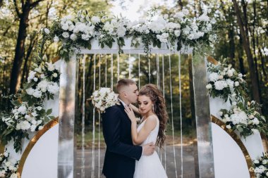 Genç bir düğün çifti, özel günlerinde güzel düğün süslemelerinin önünde romantik bir anın tadını çıkarır..